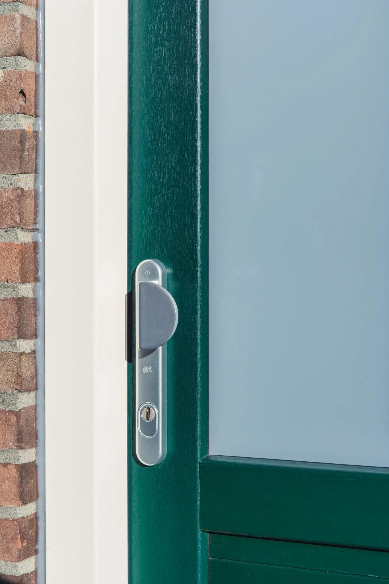 Close-up van het moderne deurbeslag en cilinderslot op een groene kunststof voordeur met matglas.